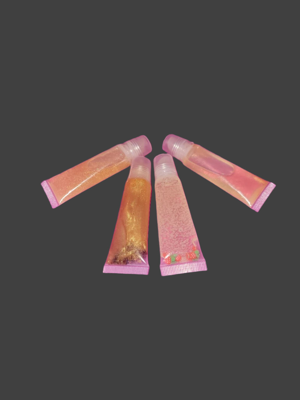 Five small lip balm tubes on a pink surface with a dark purple background